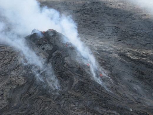USGS photo: The Kahaualeʻa 2 flow, which is active north of Puʻu ʻŌʻō, is fed from a vent at this cone on the northeast rim of Puʻu ʻŌʻō crater. Small openings at the top of the cone contain sloshing lava, and two skylights at the very start of the Kahaualeʻa 2 lava tube provided views of a swiftly moving lava stream rushing downslope.