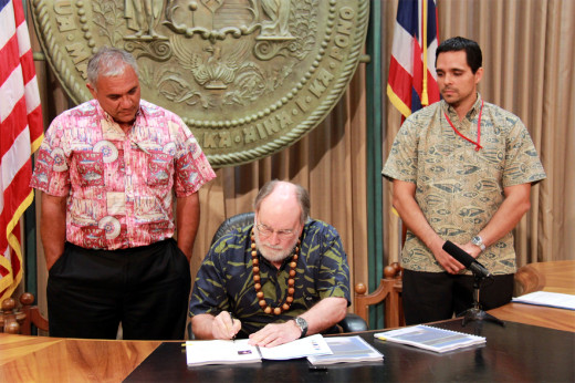 DLNR chair William Aila (left) and Office of Planning Director Jesse K. Souki (right) watch as Governor Neil Abercrombie signs the Hawaii Ocean Resources Management Plan 