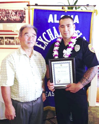 Aloha Exchange Club President Jay Kimura, presents an "Officer of the Month" plaque to Officer Shea Nactor.