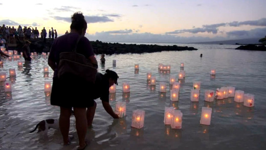 Lanterns let go, floating in the calm waters of the bay