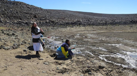 A September photo shows Pua Case and her cousin Kanoe, who is seen kneeling by the vanishing lake with spring water brought from Hilo, a gesture to "start to refill the lake".