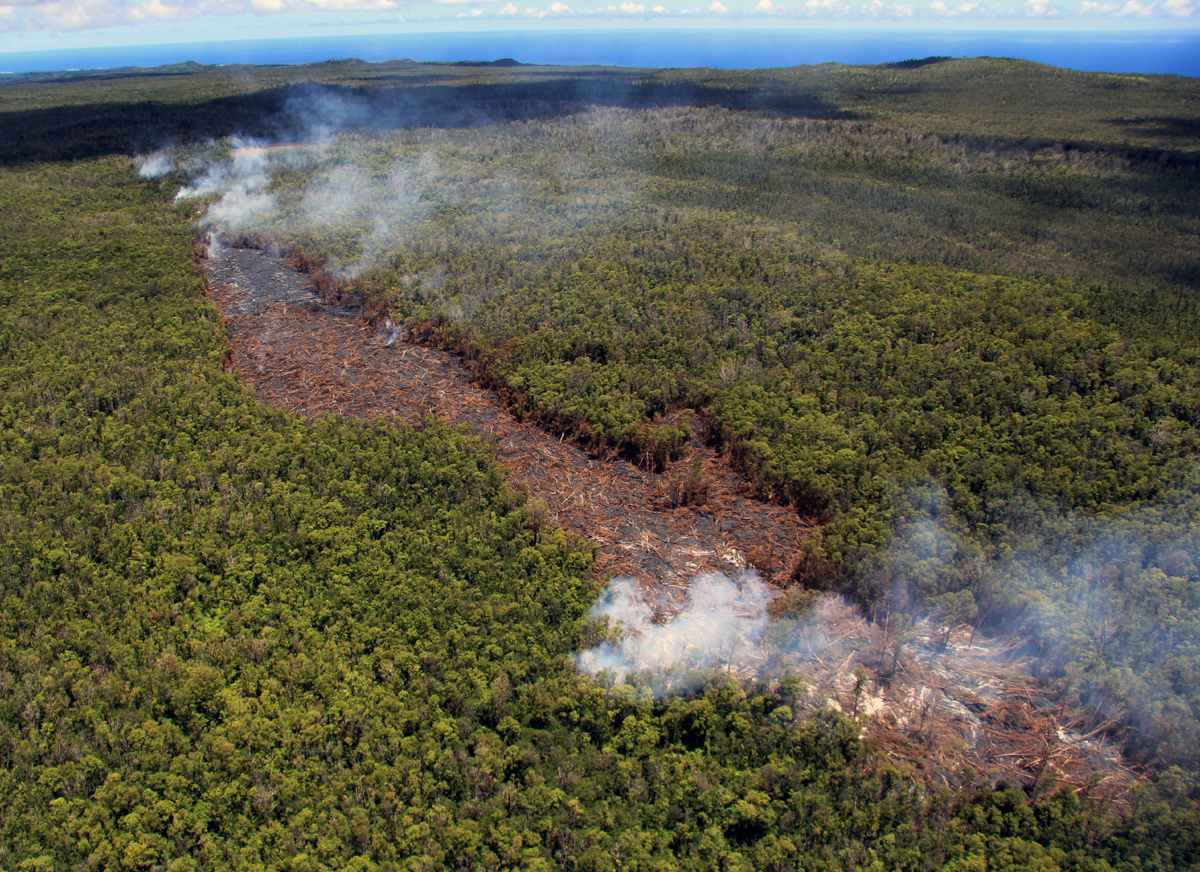 A closer view of the pad of lava that emerged from the ground crack earlier this week, which had renewed surface flows today. At the east end (upper left in photograph) of the lava pad new breakouts spilled into adjacent ground cracks, and lava was visible within the ground crack extending farther to the east (visible by line of smoke extending towards upper left portion of photo). Heiheiahulu is visible in the upper right. (USGS HVO)