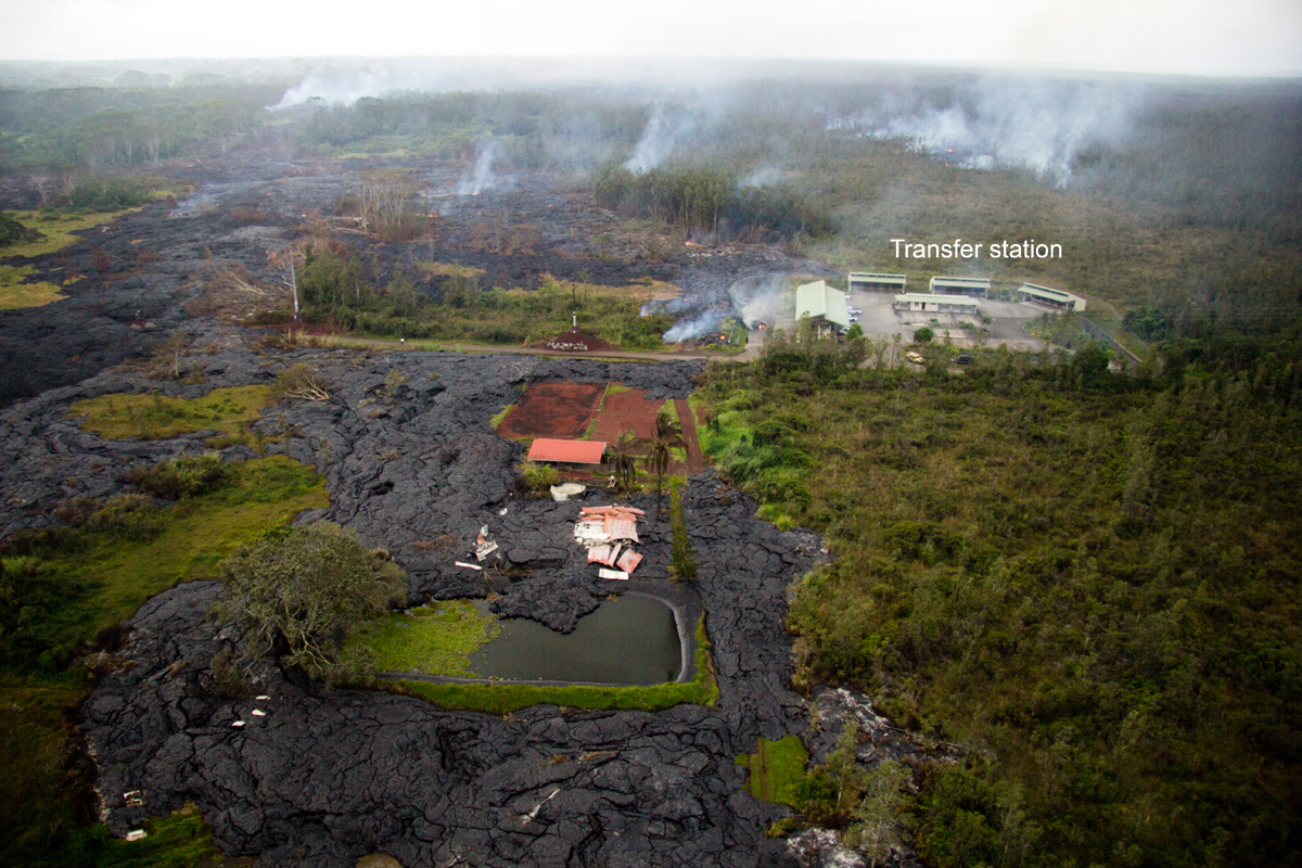 This USGS HVO photo shows the house which was recently destroyed by lava, just below the center of the picture. Lava bypassed the garage, which still stands at the center of the photo. Lava briefly entered the fish pond next to the house, before continuing downslope. Also visible is the small active flow next to the transfer station, and the larger, more rapidly moving finger about 360 meters (390 yards) upslope from Apaʻa Street at upper right. The smoke at upper left marks another breakout widening the flow into the adjacent forest. The view is to the southwest. (Nov. 12, 2014)