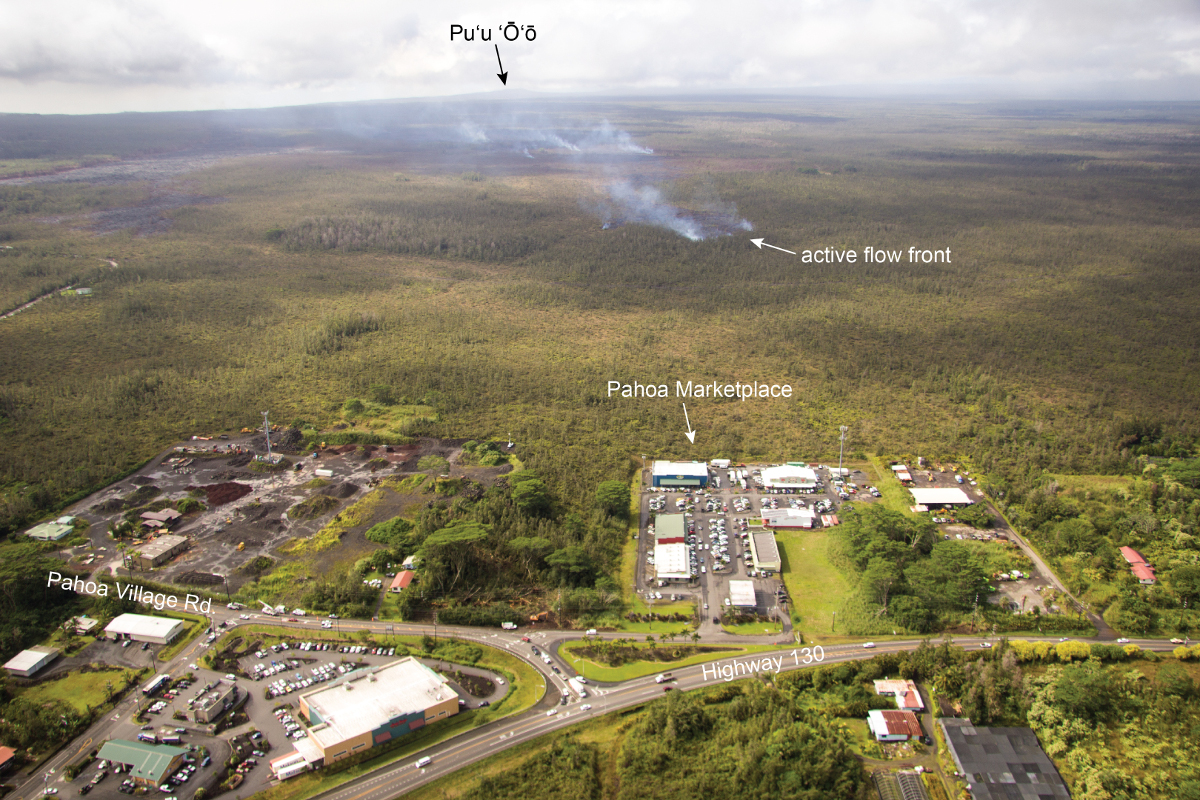 This USGS photo shows the leading tip of active lava on the June 27th flow advancing downslope, through thick vegetation, towards the northeast, with Pahoa Marketplace and Highway 130 in the foreground.
