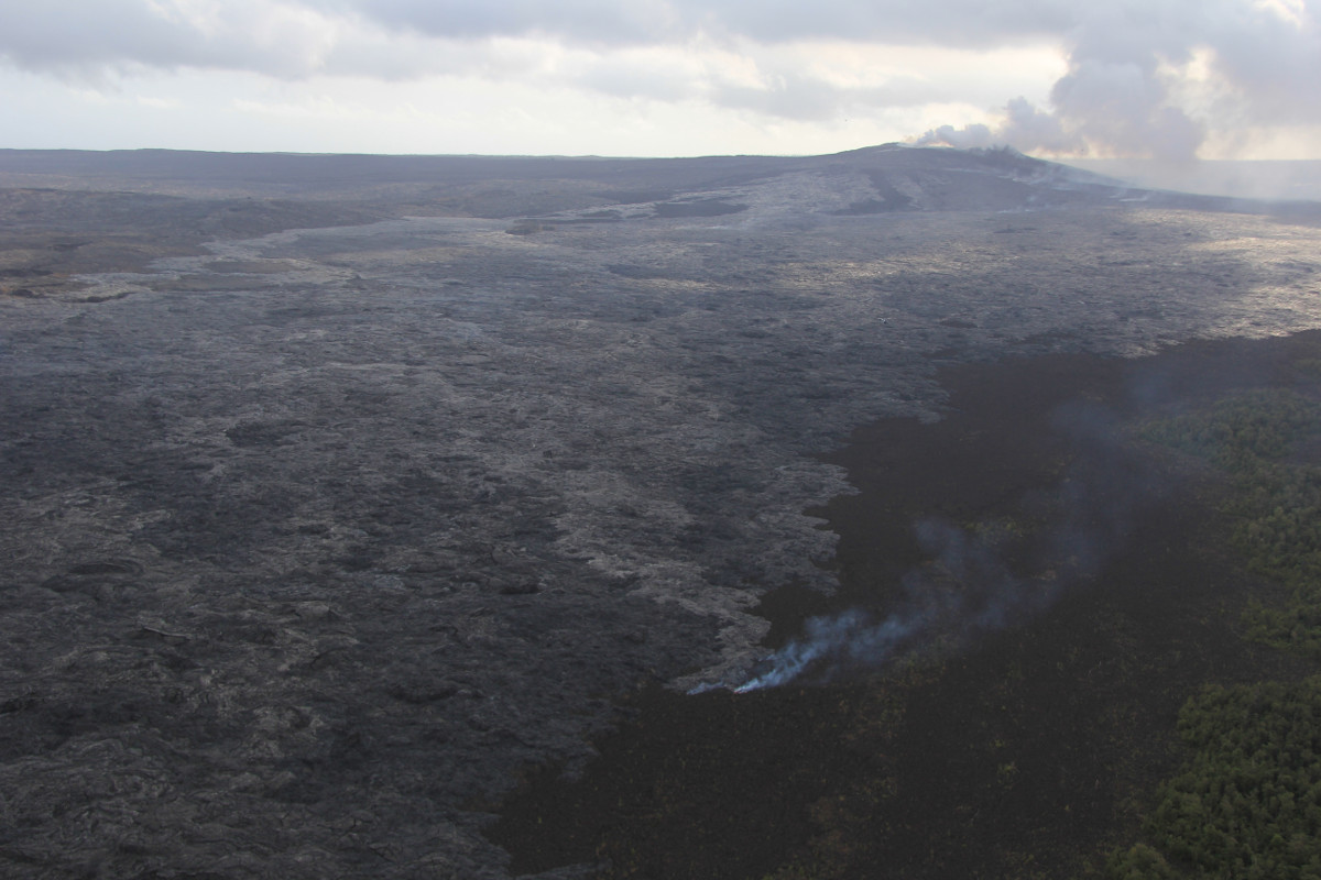 This USGS photo shows a breakout from the lava tube that has been active on the upper part of the flow field near Puʻu ʻŌʻō since December 5. The smoke is from a narrow finger of lava burning lichen on an older Puʻu ʻŌʻō lava flow. Puʻu ʻŌʻō is at upper right. The view is to the south-southwest.