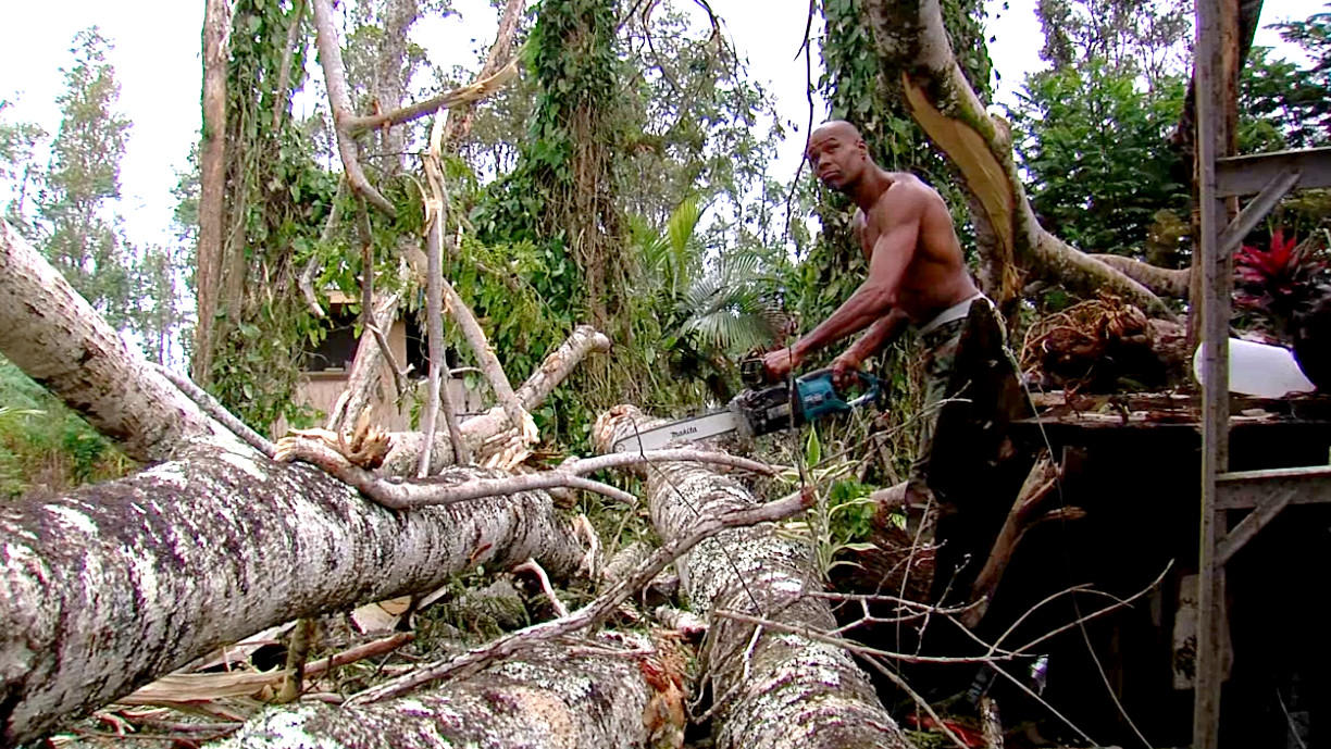 Ira, an artist and resident of Nanawale Estates, cuts his way out of a fallen albizia tree. The tree crushed his studio area outside his home.