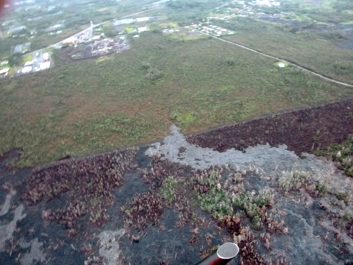 Civil defense image from this morning’s overflight (Thursday, 3/12/15) shows the view from the south flow margin, looking down slope towards Hwy 130, Pahoa Marketplace, and Apaa Street. The breakout, which had been advancing over the last few days, appeared inactive today.