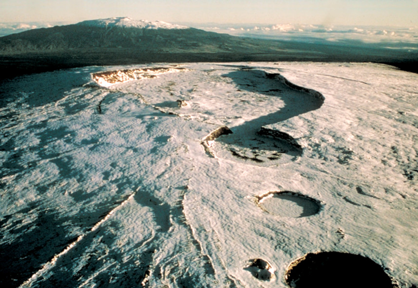 (from USGS Fact Sheet) Aerial photograph looking north-northeast across the summit area of Mauna Loa (elevation 4,169 meters or 13,679 feet). At the summit is Moku’aweoweo Caldera, a volcanic depression 3 miles (5 kilometers) long. The pit craters in the foreground are part of the upper southwest rift zone. Mauna Kea Volcano rises on the skyline.