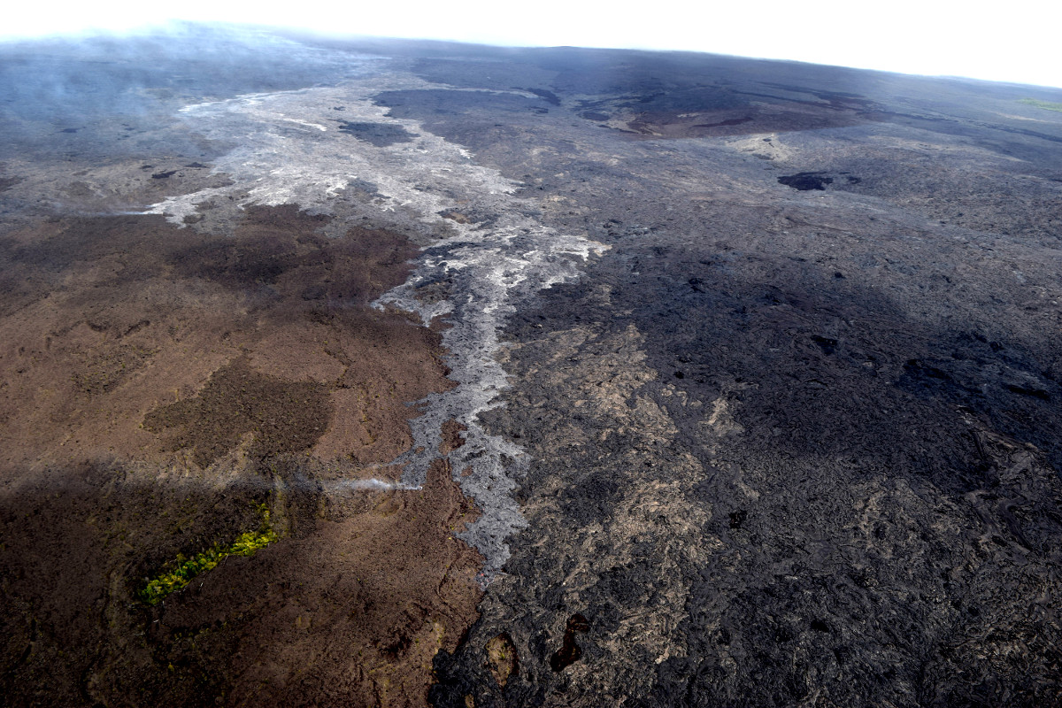 (USGS photo) This view is of the front of the active lava flow, looking upslope. Puʻu ʻŌʻō is partly obscured in the clouds at upper left. Most surface activity on the advancing flow is actually where the flow widens, upslope of the flow front.