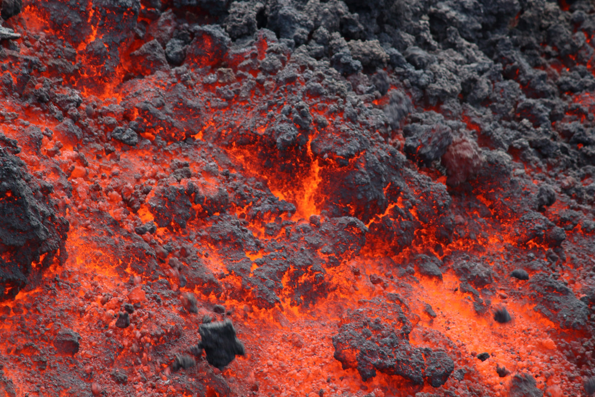 (USGS photo) Another view of the flow front, contrasting the hot fluid core of the flow (red) with the brittle clinker (black) that forms the flow exterior.