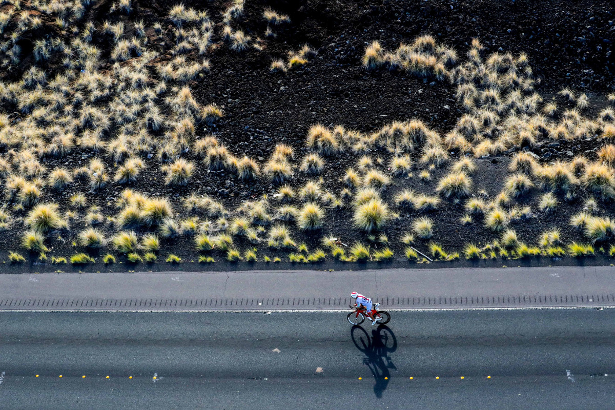 LONESOME RIDER. Surrounded by an unforgiving sun and barren lava fields, a lone athlete treks along the 112-mile bike course at the 2016 IRONMAN World Championship in Kailua-Kona, Hawai’i. (Tom Pentington/Getty Images for IRONMAN) - Copyright © 2016 IRONMAN