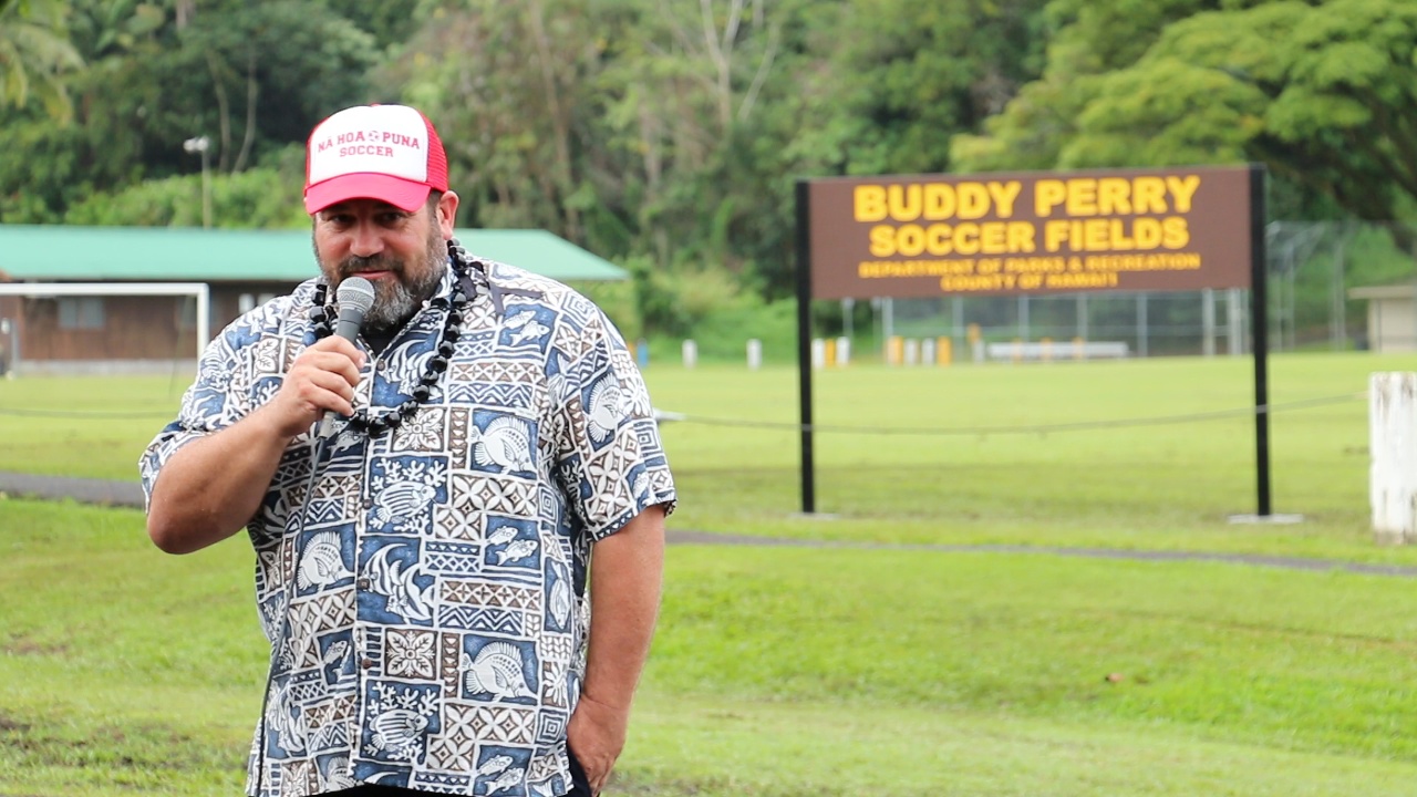 Dan Bielger speaks with the new Buddy Perry Soccer Field sign behind him
