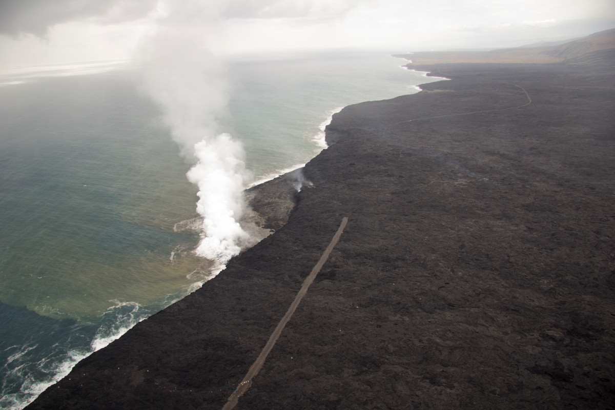 A lava delta about 19 acres in size has been built by the lva flow, USGS reports. The gravel emergency access road is visible on both sides of the surface flow that cut it. The view is to the southwest.